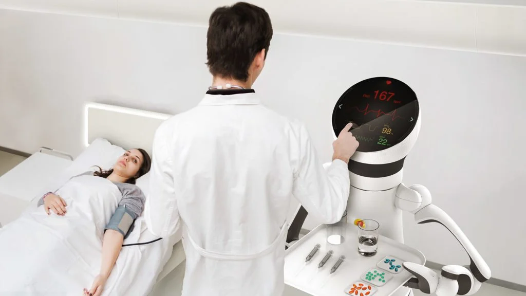 Care-o-bot hastene kullanımına örnek. Robot bir yandan tepsi içinde ilaçları tutarken, bir yandan da ekranında doktora hastanın hayati değerlerini gösteriyor.